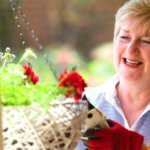Female resident pruning pot plants outside her home at St Ives retirement village
