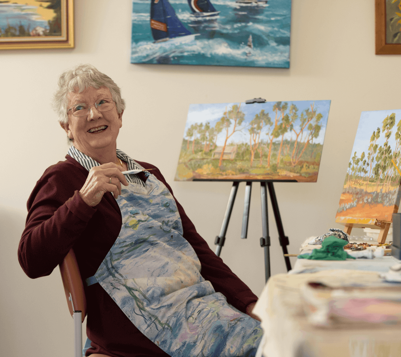 Elderly woman painting an Australian landscape
