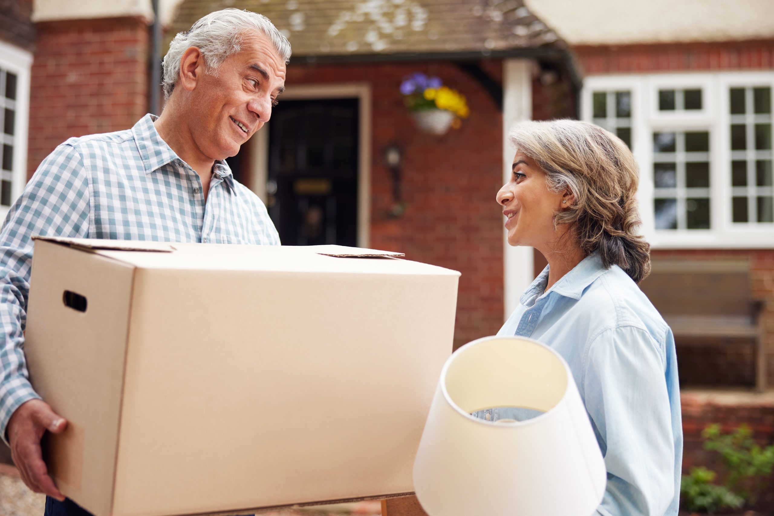 Couple with a box and lightshade who look like they're moving house